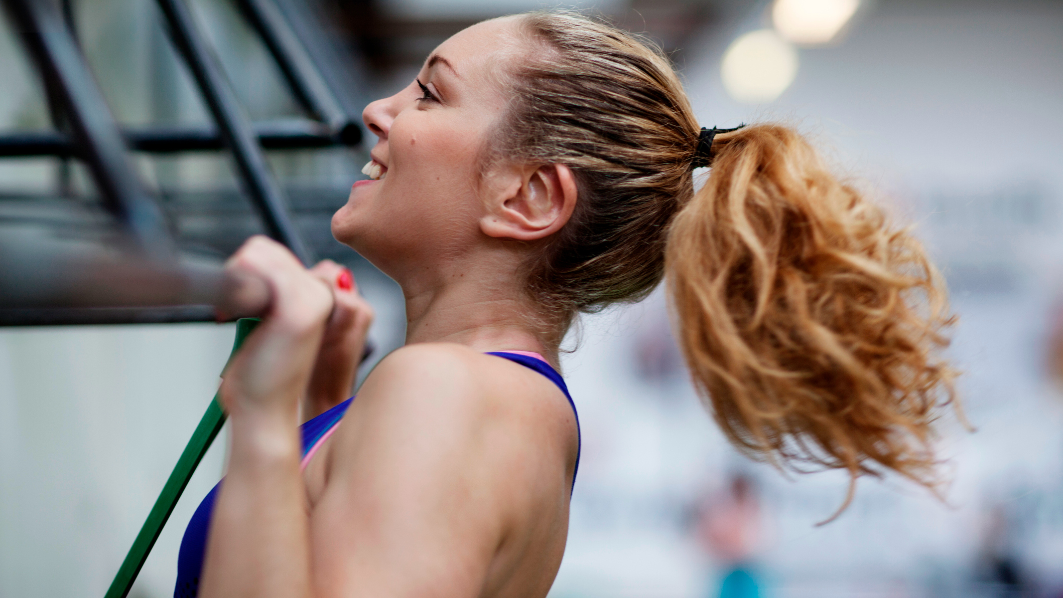 Close-up of woman’s head performing a pull-up, with her chin over the bar